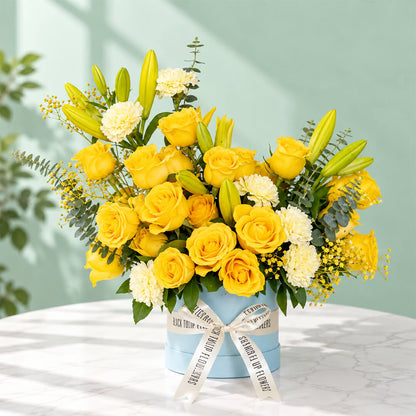 Yellow rose, carnation and lily flower arrangement with gypsophila and eucalyptus, presented in a round blue flower box.