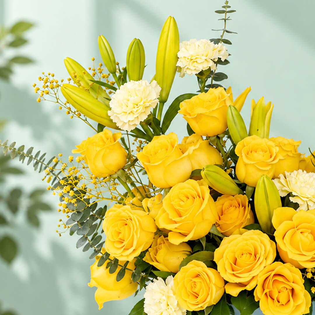 Yellow rose, carnation and lily flower arrangement with gypsophila and eucalyptus, presented in a round blue flower box.