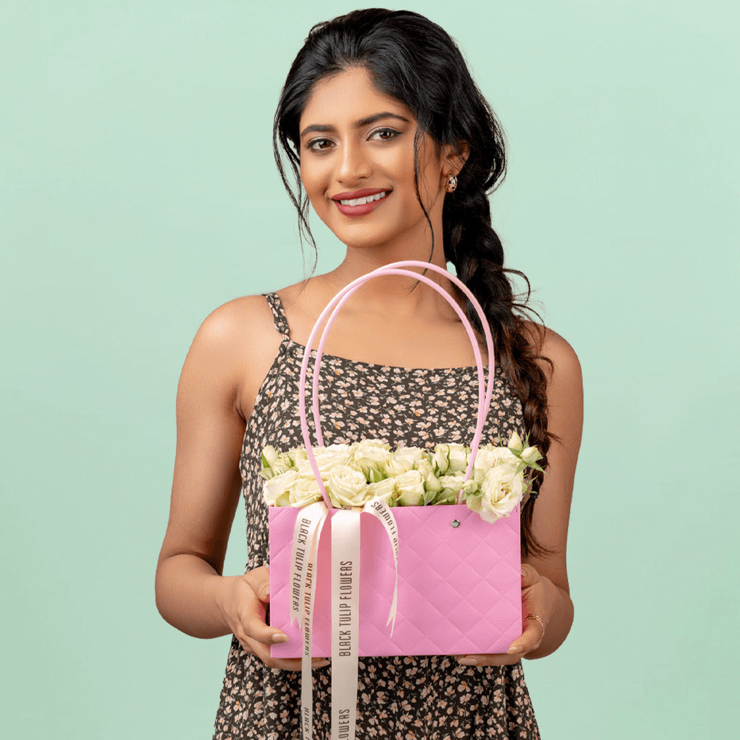 White spray roses arranged in a quilted pink flower bag for elegant gifting