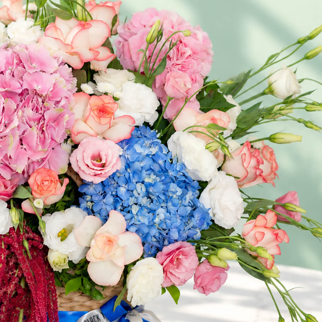 Mixed floral basket with hydrangea, roses, eustoma and amaranthus arranged in a rectangular basket