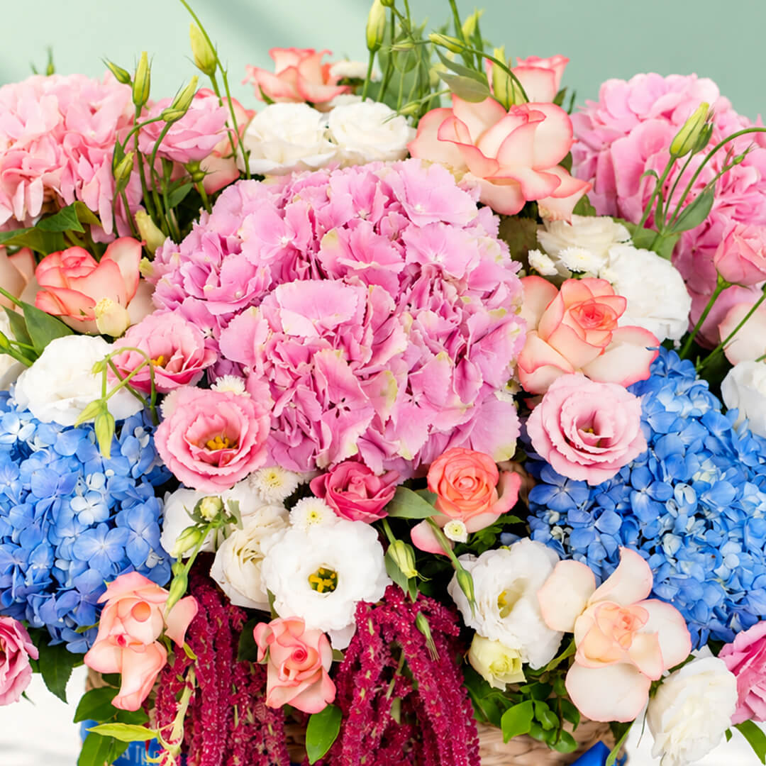 Mixed floral basket with hydrangea, roses, eustoma and amaranthus arranged in a rectangular basket