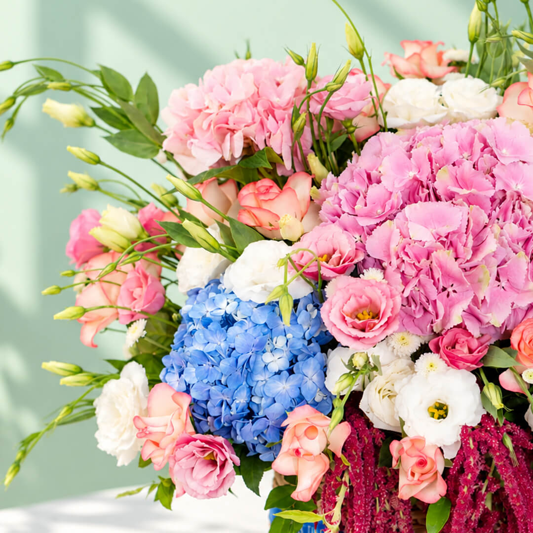 Mixed floral basket with hydrangea, roses, eustoma and amaranthus arranged in a rectangular basket