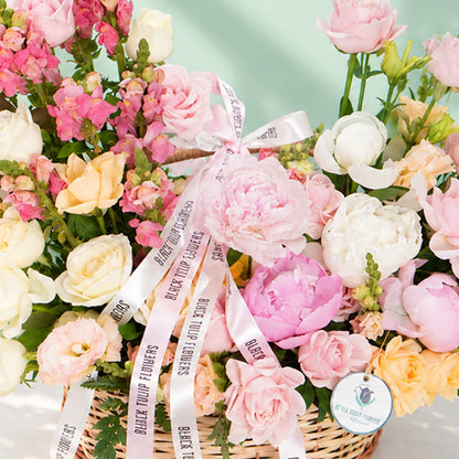Mixed blooms including roses, peonies, carnations and snapdragons arranged in a basket