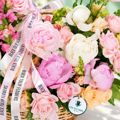 Mixed blooms including roses, peonies, carnations and snapdragons arranged in a basket