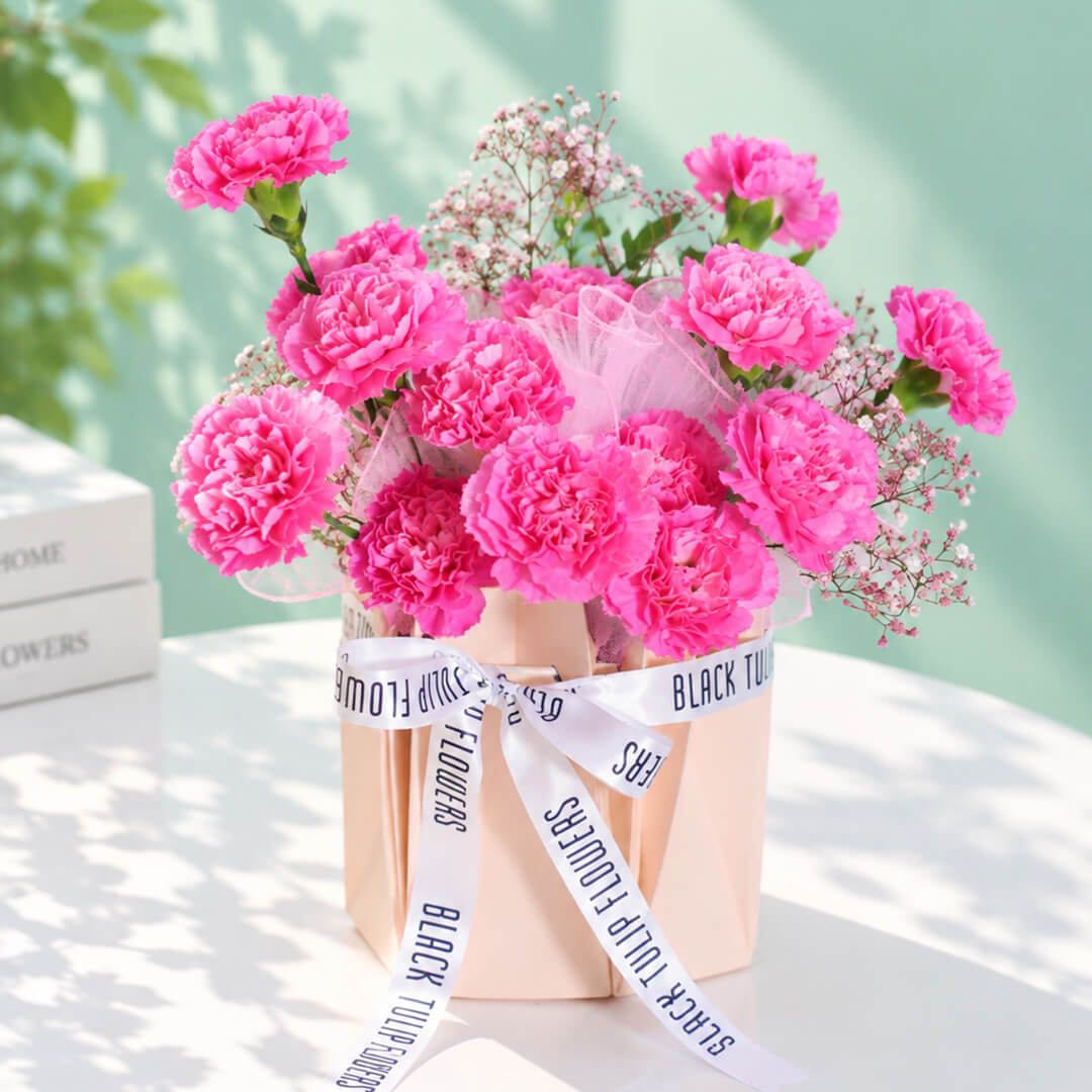 Pink carnations and gypsophila arranged in a decorative flower bag