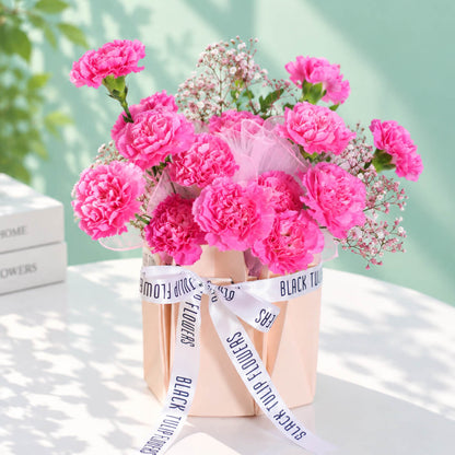 Pink carnations and gypsophila arranged in a decorative flower bag
