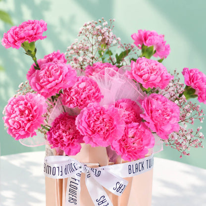 Pink carnations and gypsophila arranged in a decorative flower bag