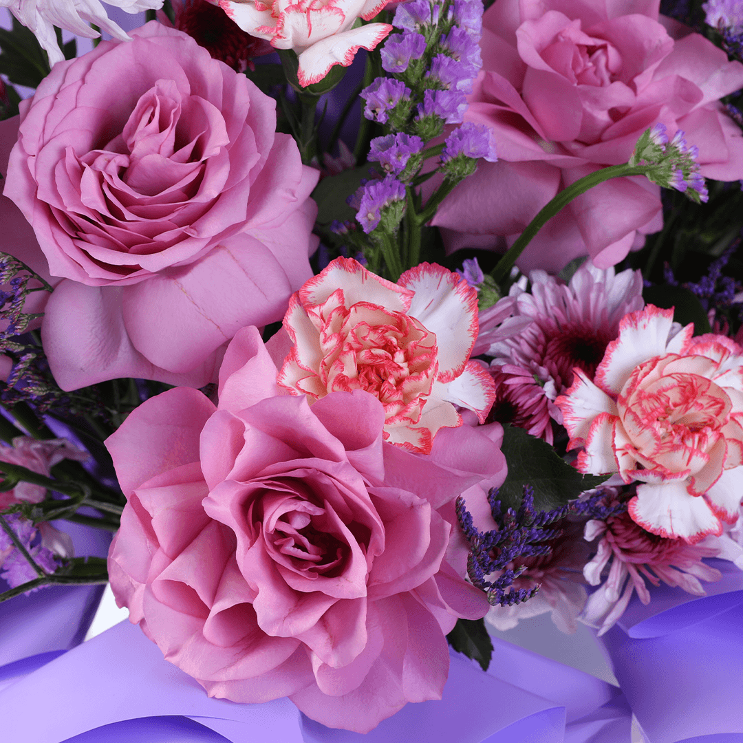 Pink and purple mixed flowers in a white round box