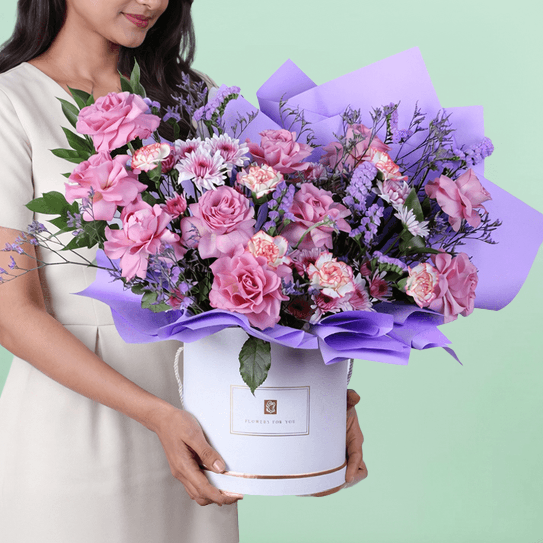 Pink and purple mixed flowers in a white round box