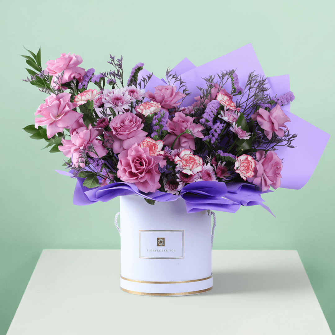 Pink and purple mixed flowers in a white round box