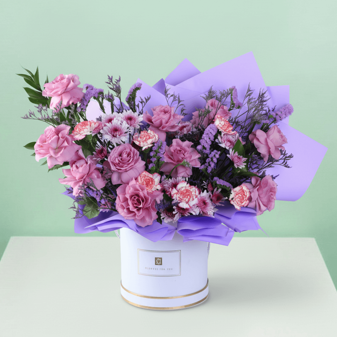 Pink and purple mixed flowers in a white round box