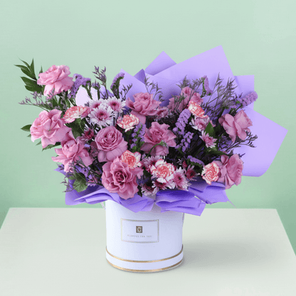 Pink and purple mixed flowers in a white round box