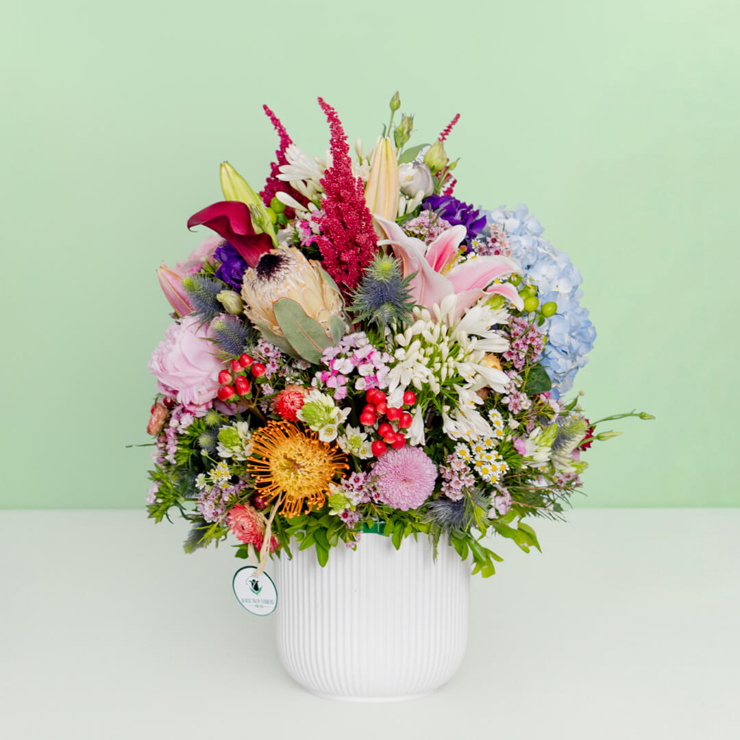 Exotic flower vase with protea, hydrangea, pincushion, lilies and greenery