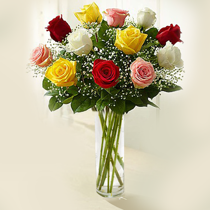 A transparent glass cylinder vase arrangement featuring 12 assorted roses, baby’s breath and greenery.