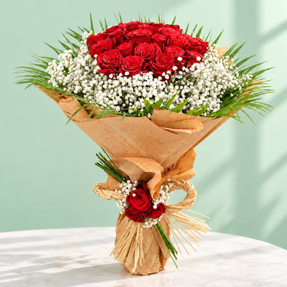 A bouquet featuring 30 red roses with delicate white gypso flowers nestled between the roses and a neat non-woven paper finish