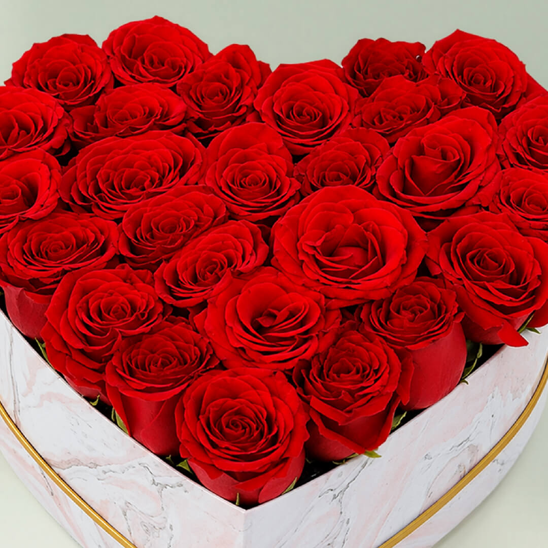 Fresh red roses arranged in a white heart-shaped marbled box for romantic gifting