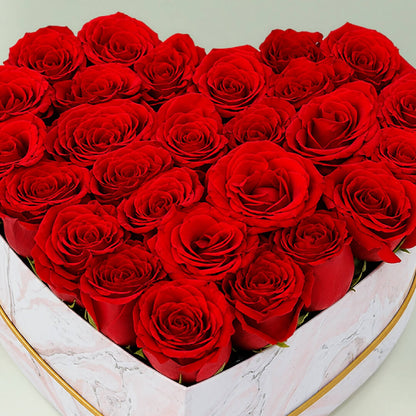 Fresh red roses arranged in a white heart-shaped marbled box for romantic gifting