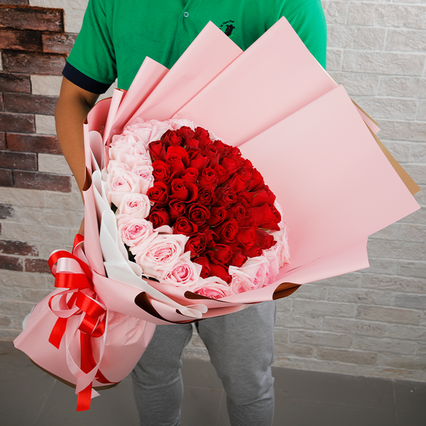 Heart-inspired bouquet of red and pink roses in soft pink wrapping