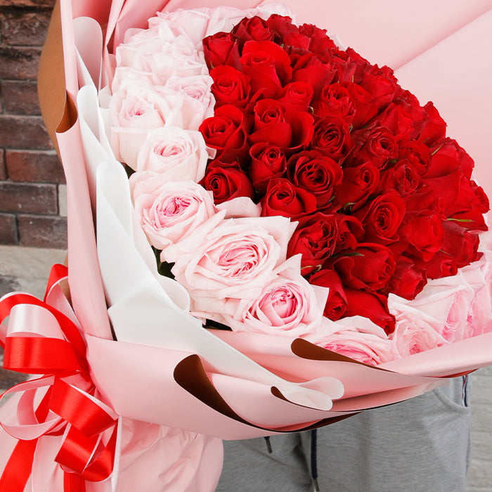 Heart-inspired bouquet of red and pink roses in soft pink wrapping