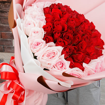 Heart-inspired bouquet of red and pink roses in soft pink wrapping