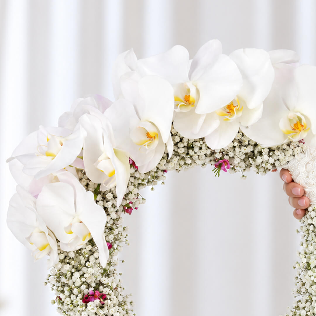 White Cymbidium bridal wreath with Gypsophila, wax flowers, and steel grass in a circular design