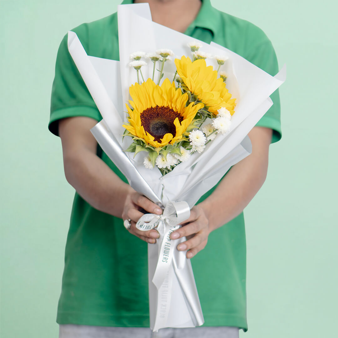 Fresh sunflower bouquet wrap with white wrapping and ribbon for cheerful gifting.