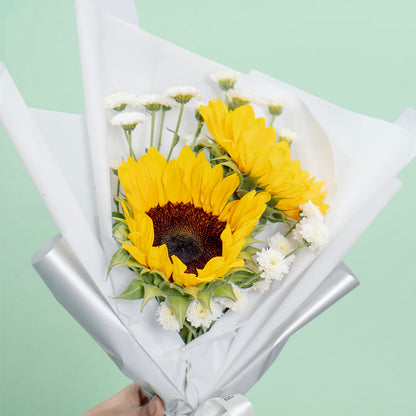 Fresh sunflower bouquet wrap with white wrapping and ribbon for cheerful gifting.