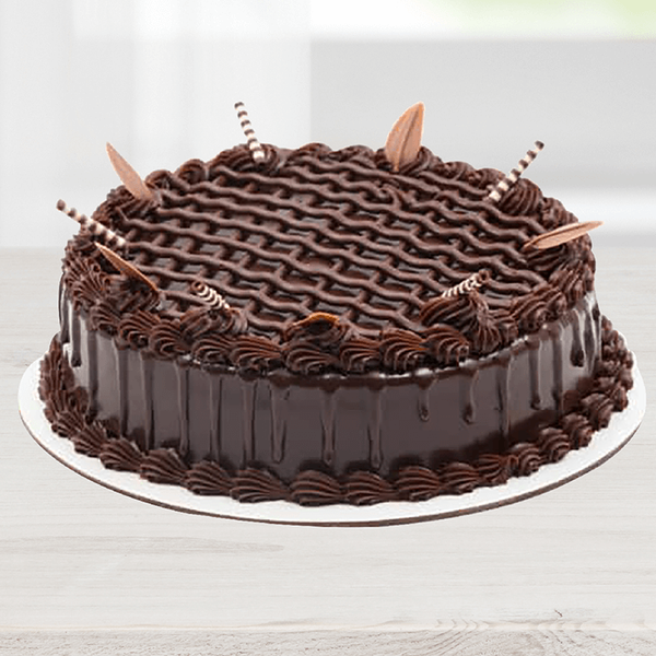 Triple Chocolate Cake featuring glossy chocolate frosting, piped swirls and decorative chocolate pieces.