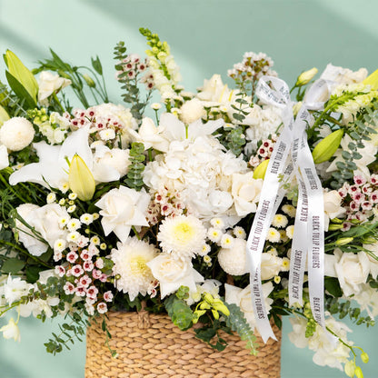 White flower basket featuring roses, hydrangea, lily and orchid with fresh greenery