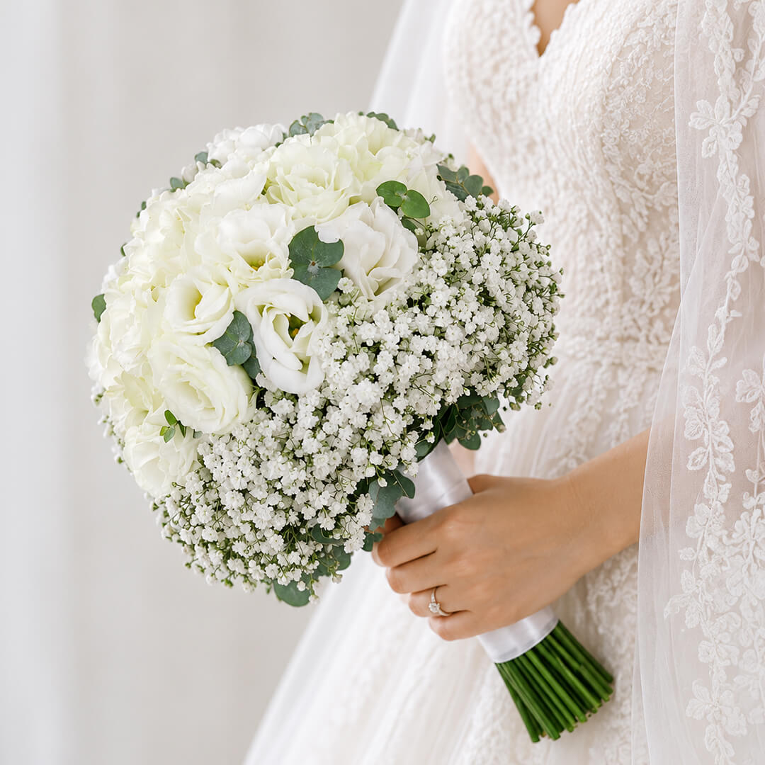 Elegant white hydrangea bridal bouquet featuring eustoma, gypsophila, and eucalyptus in a clean minimalist hand-tied stem wrap.
