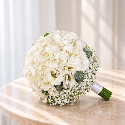 Elegant white hydrangea bridal bouquet featuring eustoma, gypsophila, and eucalyptus in a clean minimalist hand-tied stem wrap.