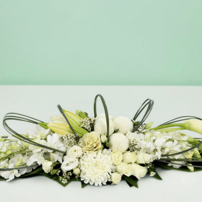 White long low flower arrangement with orchids lilies roses chrysanthemums and fresh greenery