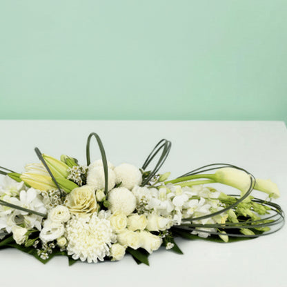White long low flower arrangement with orchids lilies roses chrysanthemums and fresh greenery