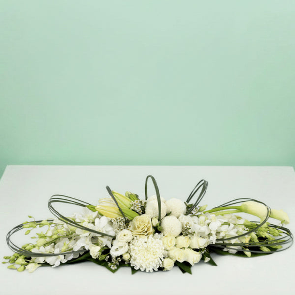 White long low flower arrangement with orchids lilies roses chrysanthemums and fresh greenery