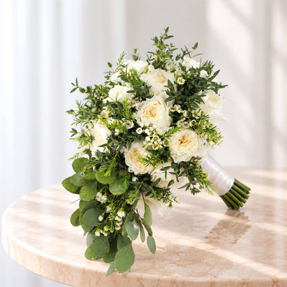 Premium white rose bouquet with a minimalist hand-tied design, accented with eucalyptus and wax flowers.