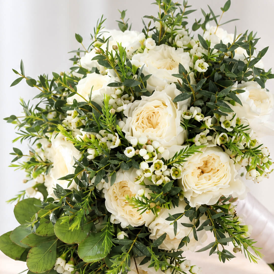 Premium white rose bouquet with a minimalist hand-tied design, accented with eucalyptus and wax flowers.