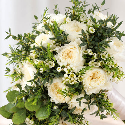 Premium white rose bouquet with a minimalist hand-tied design, accented with eucalyptus and wax flowers.