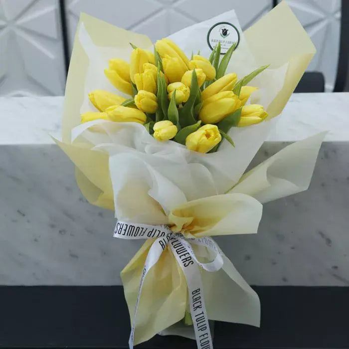 Bouquet of 20 fresh yellow Tulips wrapped in elegant cream non-woven paper.