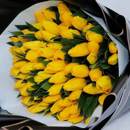 Yellow tulips arranged in layered black and white non-woven wrapping