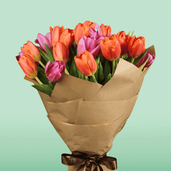 Stunning orange and pink tulips bouquet wrapped in a grey cellophane sheet.