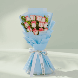 A bouquet of 12 white roses with green leaves, wrapped in bright fuchsia pink non-woven paper and tied with a white and black ribbon.