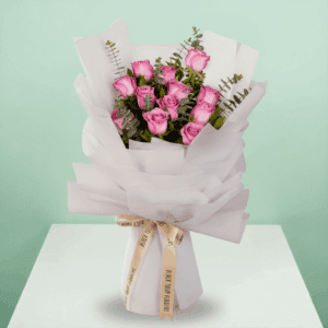 A bouquet of purple roses with green eucalyptus branches, wrapped in white non-woven paper and tied with a beige ribbon - 12 Roses Bouquet