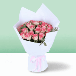 A blush pink roses bouquet wrapped in elegant white paper with greenery and pink ribbon.