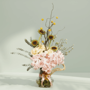 Beautiful sunflower and rose flower arrangement with crespedia, eucalyptus, wax flowers, and curly salix styled in a clear glass vase.